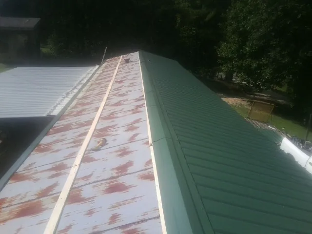 Old rusted panels beside newly installed green metal roofing — Wind Damage Roof Repair by Roofing Brothers in Kansasville