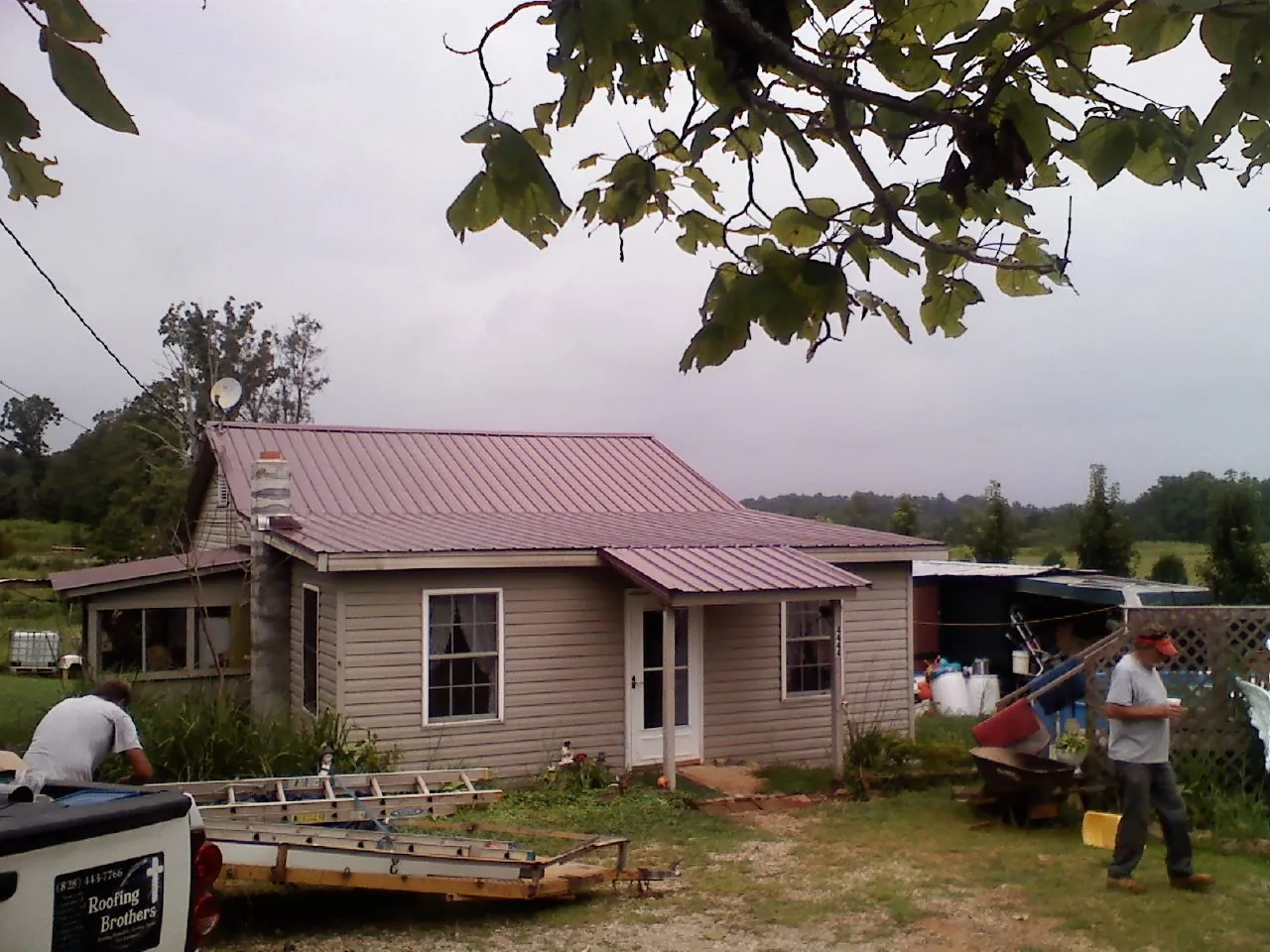 Crew finishing a mauve metal roof on a small farmhouse in Kansasville
