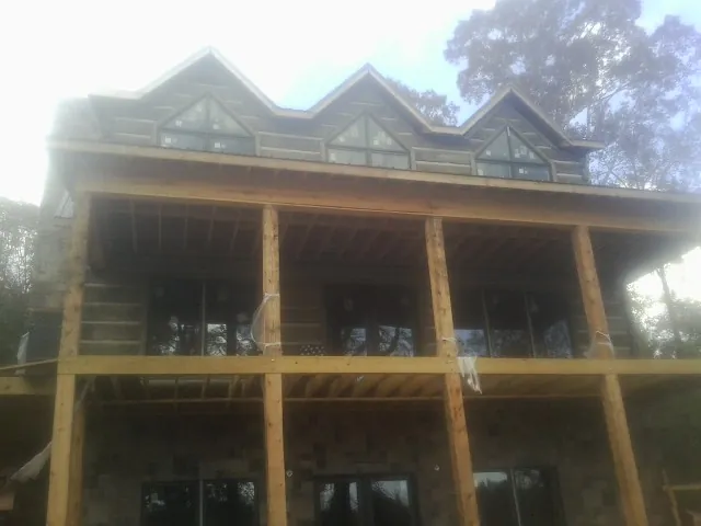 Dormers and porch framing on a large log home under construction — Roof Coating work by our crew in Kansasville