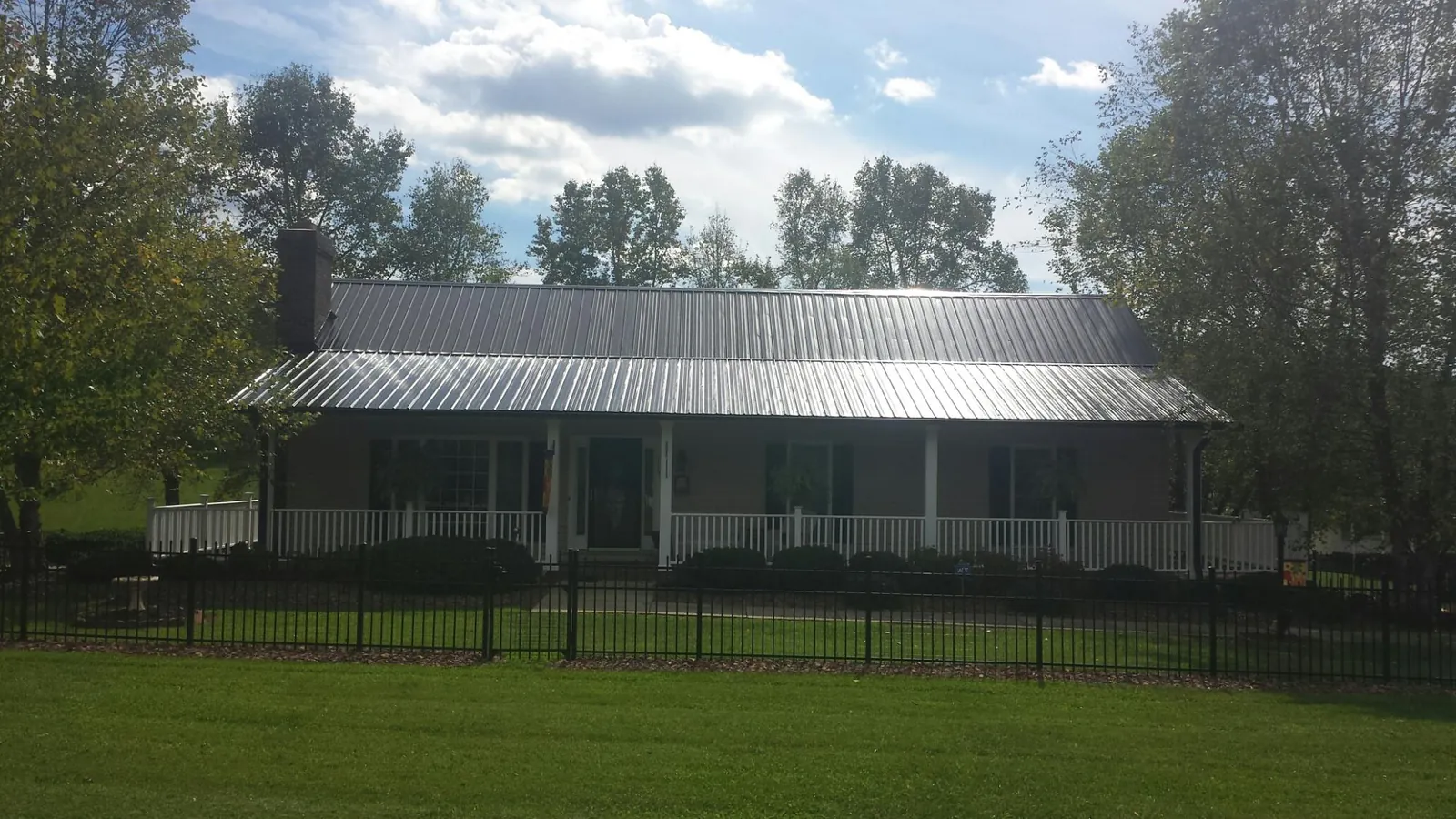 Gray metal roof on a brick ranch with a full width front porch — Gutter Guard Installation work by our crew in Kansasville