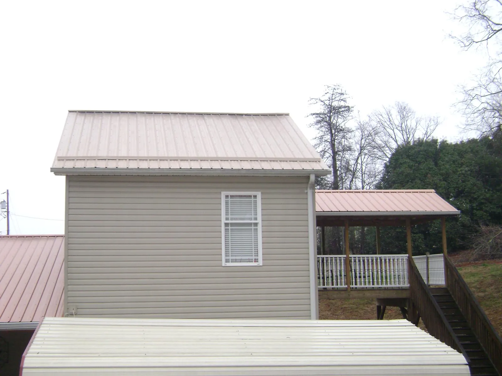Tan metal roofs on a two story addition and attached porch, from a Roof Replacement job in Kansasville