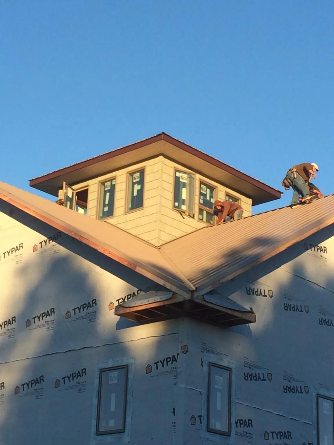 Roofers working around a rooftop cupola on a new metal roof at sunset — Roof Waterproofing in Kansasville by Roofing Brothers